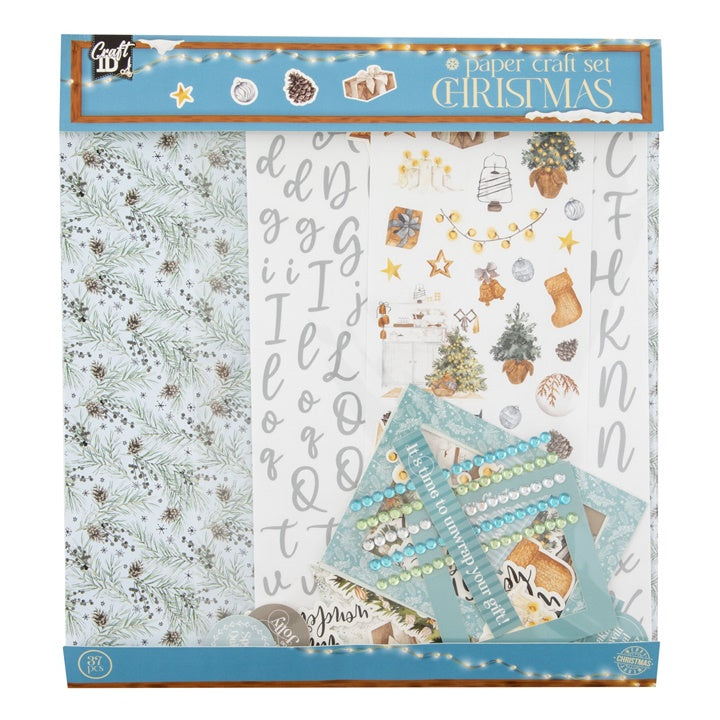 Božićni set za scrapbooking u plavim tonovima sa ukrasnim papirima i naljepnicama za kreativne projekte.